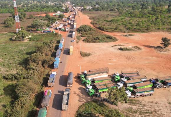 This aerial view shows Malian trucks waiting to cross the border between Ivory Coast and Mali in the village of Nigoun, near Tengrela on October 31, 2025. In northern Ivory Coast, truck drivers prepare to head back to neighbouring Mali, aboard their tanker trucks loaded with fuel and anxiety. One acronym strikes fear into the hearts of all the truck drivers: JNIM, the name of the jihadist group affiliated with Al-Qaeda that decreed two months ago that no more tanker trucks would be allowed to enter Mali from a neighboring country.
Since then, hundreds of trucks have been set ablaze, selling fuel from Abidjan or Dakar, and are part of JNIM’s economic jihad strategy, which aims, among other things, to strangle Bamako and the ruling military junta.
In 2023, more than half of the petroleum products exported by Côte d’Ivoire were destined for Mali. Malian trucks load up in Yamoussoukro or Abidjan before crossing one of two corridors into the country: the Tengréla corridor or the Pogo corridor, where military escorts take over on the Malian side, all the way to Bamako. An escort can consist of several hundred tankers.
But even under escort, convoys are frequently targeted. The most dangerous areas in southern Mali are the Kadiana-Kolondiéba and Loulouni-Sikasso axes. (Photo by Issouf SANOGO / AFP)